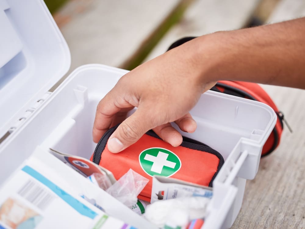 A hand pulling a small first aid kit from a larger white box.