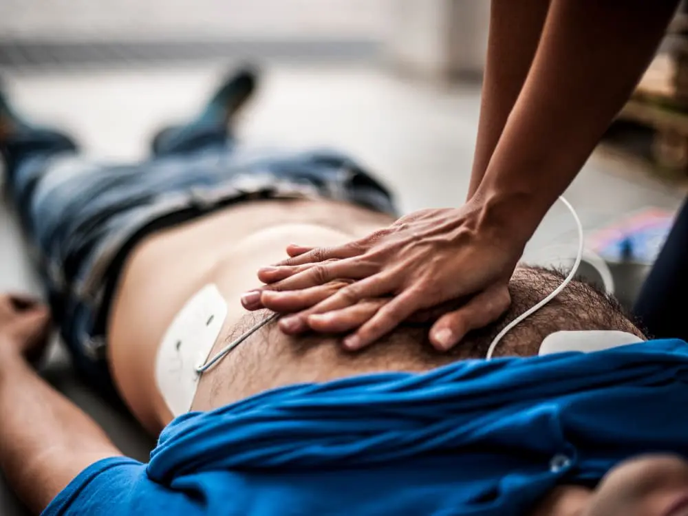 A man laying on his back is having heart compressions performed on him.