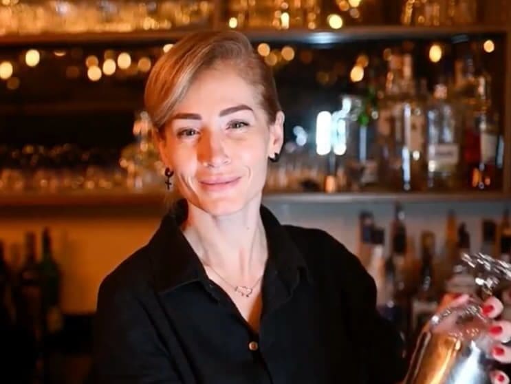 A woman in a fancy bar shaking a cocktail shaker