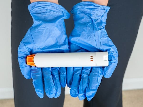 Blue gloves holding an EpiPen