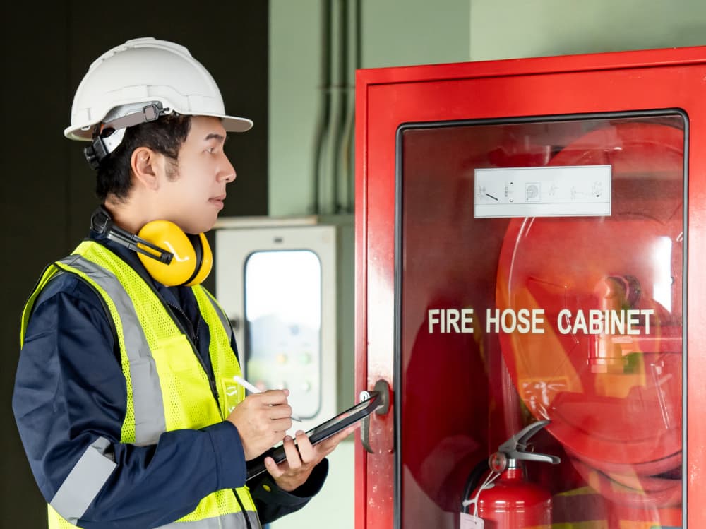 Man with a clipboard standing in front of a fire hose cabinet