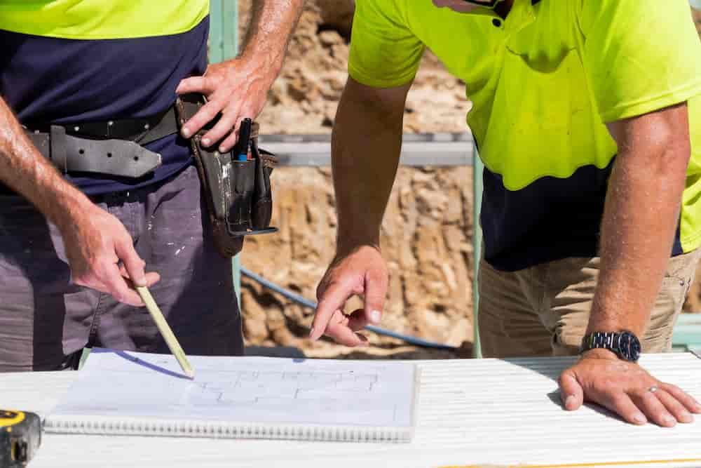 Two builders discussing plans in the sunlight